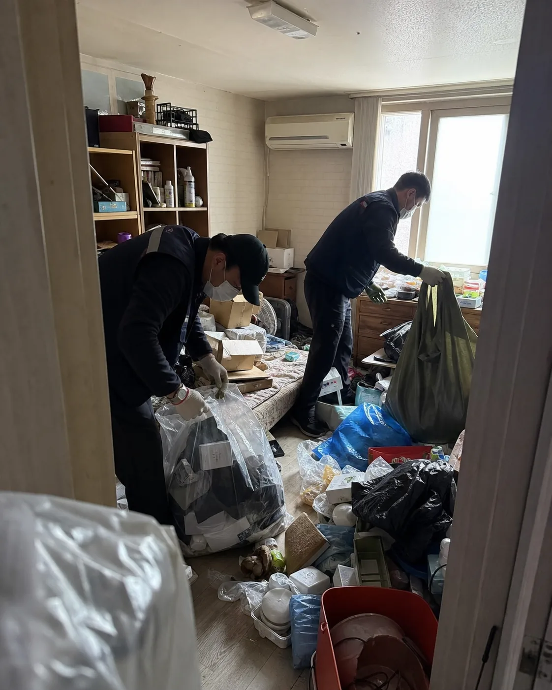 작업자 두 명이 실내 생활폐기물을 분류하고 봉투에 포장하는 실제 특수청소 작업사진